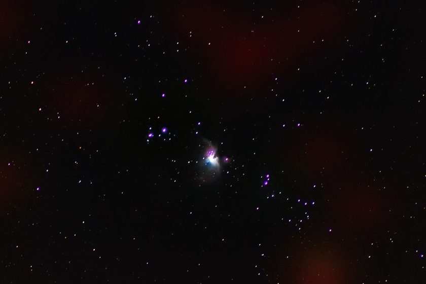 Faint nebula glow through binoculars above rooftops